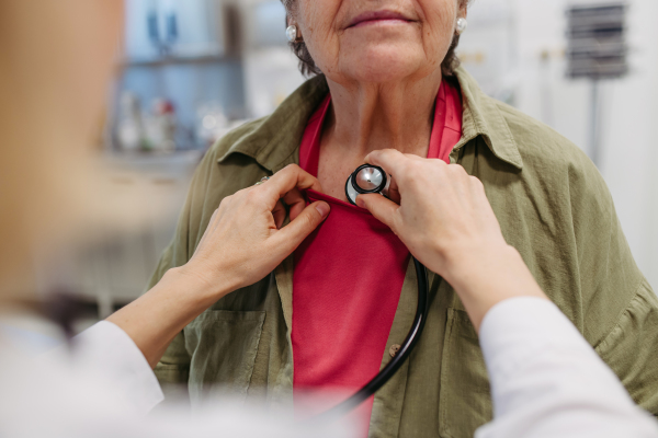 Geriatrician doctor examining elderly patient with stethoscope.. Routine health exam for elderly woman.