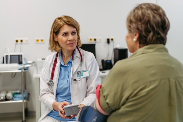 Elderly female patient undergoing blood pressure test at routine check-up. Preventive medical exam