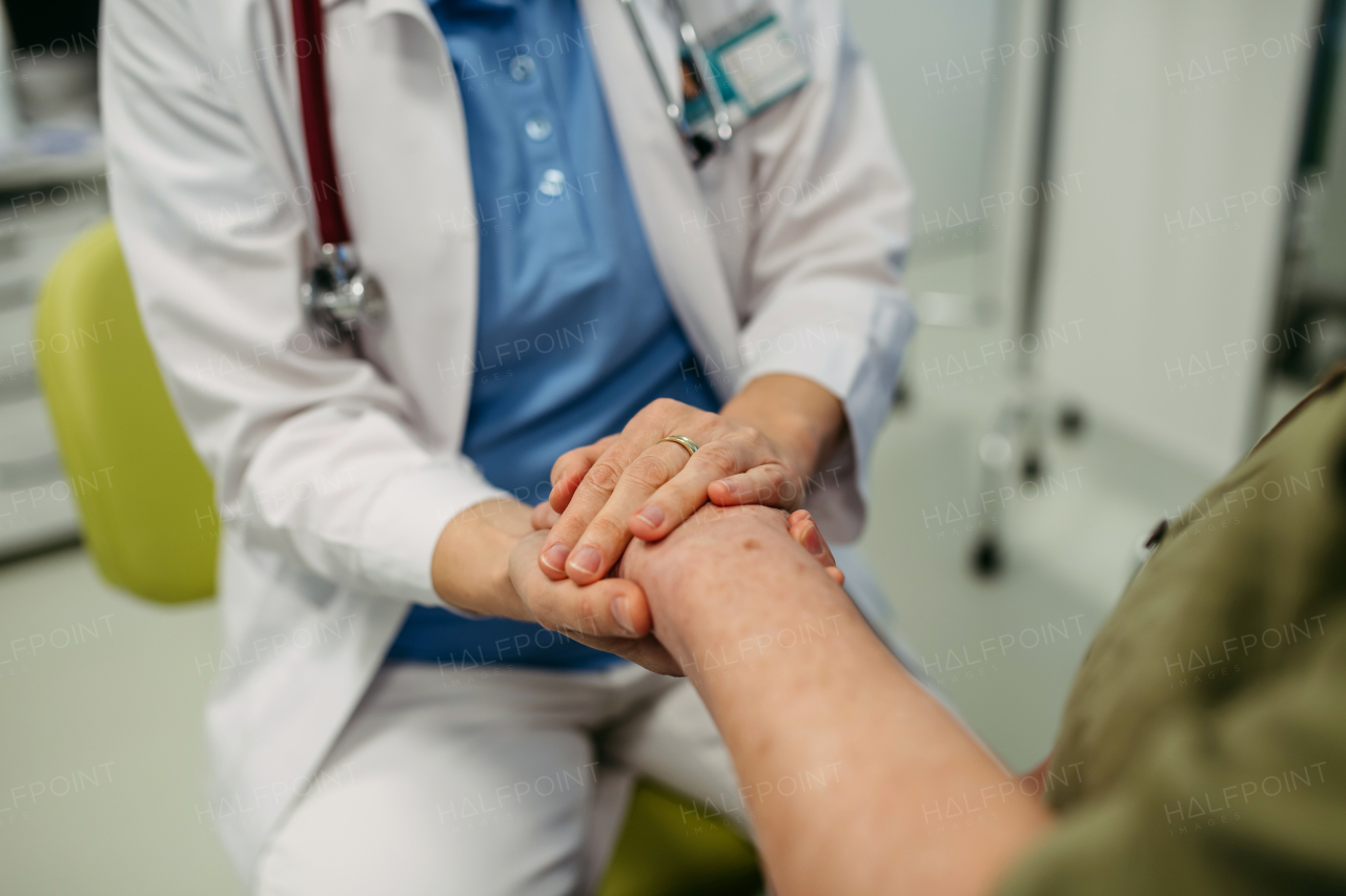 Caring doctor holding senior patient hand, compassionate gesture.