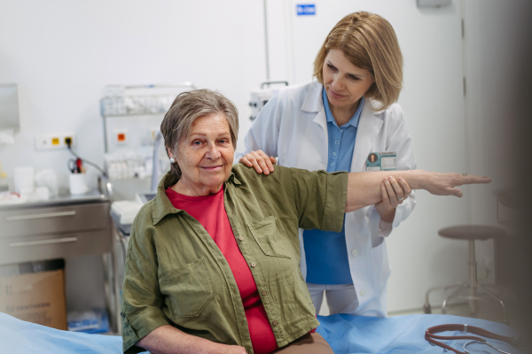 Geriatrician examining senior woman's mobility during routine check-up. Elderly care.