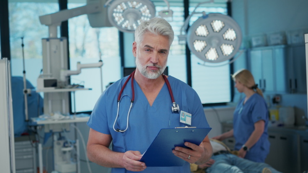 Video of older doctor standing in examination room in hospital. Banner with copy space.