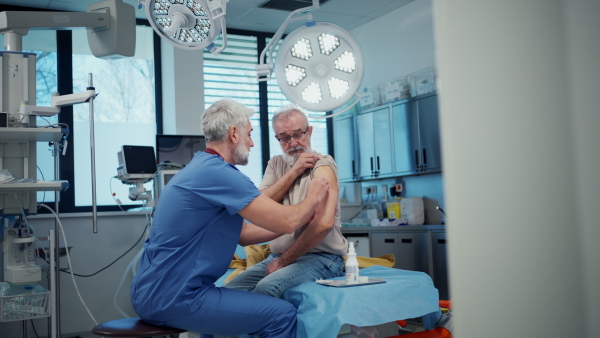 A vaccination of senior man during routine health checkup at hospital.