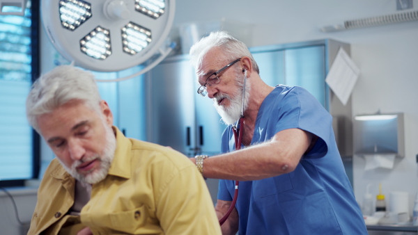 Doctor examining sick patient, listening to breathing with stethoscope.