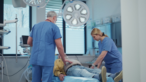 Medical professional examining patient lying on examination table. Emergency room setting.