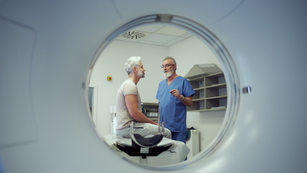 Doctor explaining CT scan results to male patient in hospital setting