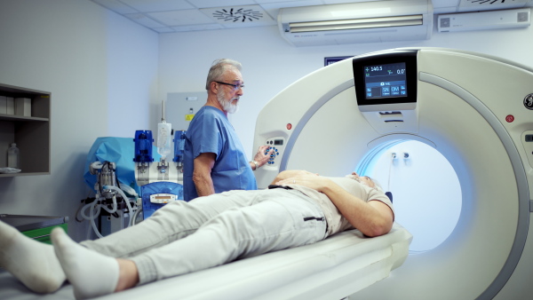 Doctor operationg CT machine in hospital. Male patient undergoing CT scan.