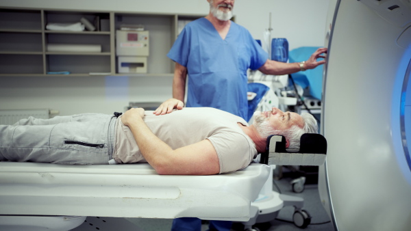 Doctor operationg CT machine in hospital. Male patient undergoing CT scan.