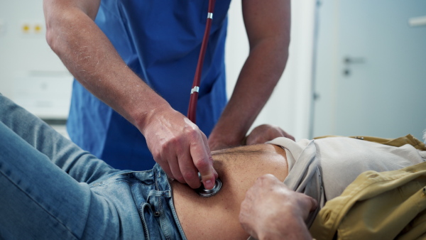 Medical professional examining patient lying on examination table. Emergency room setting.