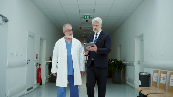 Medical sales representative presenting new medication to doctors, walking through corridor in hospital. Hospital setting.