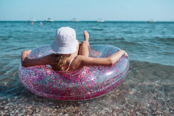 Girl on beach with swim ring. Summer beach holiday.