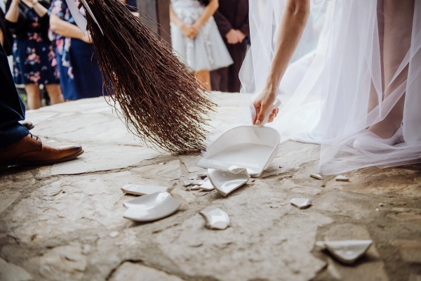 Couple sweeps broken plate at Slovak wedding.