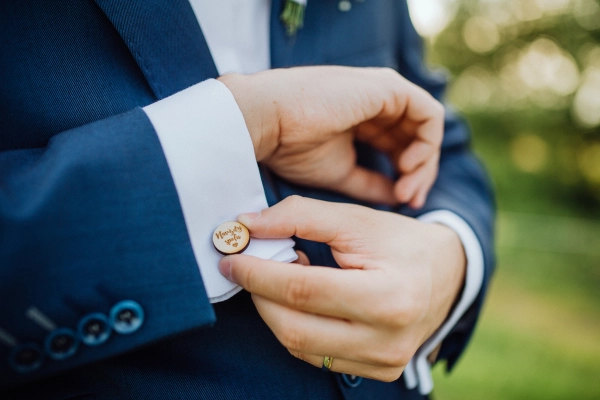 Close-up shot of groom adjusting his sleeve and cuffs.