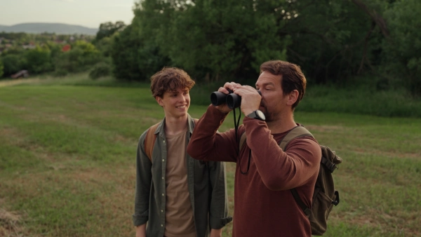 Father and teen son hiking together and observing nature.